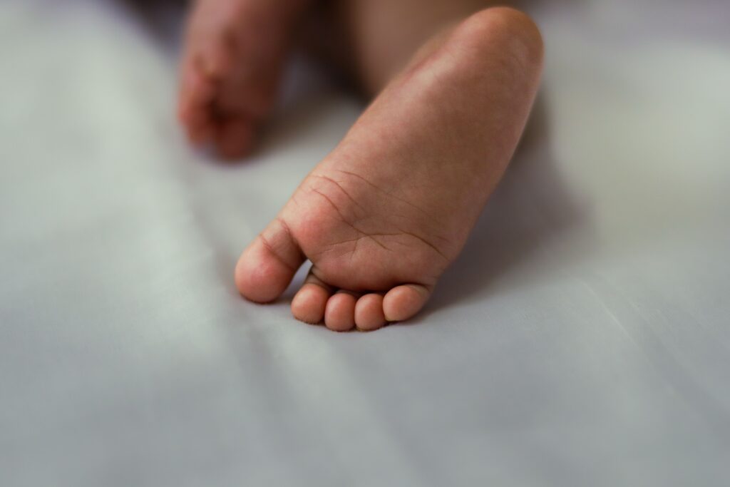 pexels-photo-38598179-38598179-1 A close-up shot of a baby's foot resting on a soft bed, conveying innocence and warmth.